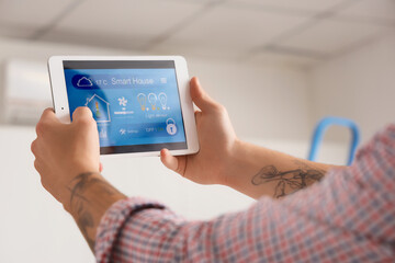 Male worker with tablet installing alarm system in house, closeup