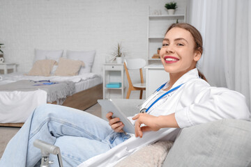 Obraz premium Female medical student studying with tablet on sofa at home