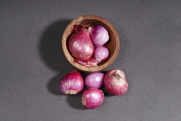 Obraz premium Red onion on wooden bowl isolated on black background.