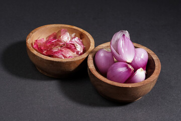 Red onion on wooden bowl isolated on black background.