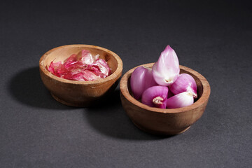 Red onion on wooden bowl isolated on black background.