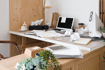 Messy workplace with laptop, garbage and papers in office