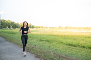 A woman is running in a park with a green field in the background