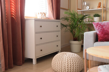 Interior of living room with sofa, drawers and curtains on window