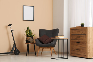 Interior of living room with electric scooter, armchair and drawers