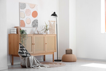 Chest of drawers, picture and floor lamp near white wall