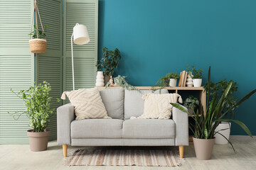 Sofa, lamp, folding screen and houseplants in interior of living room