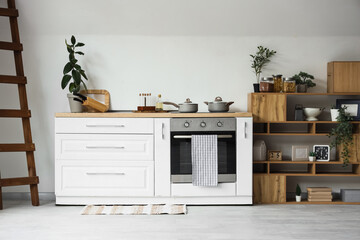 Interior of light kitchen with counter, oven and shelf unit