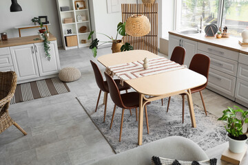 Interior of light kitchen with dining table, counters and plants