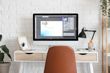 Designer's workplace with computer monitor near white brick wall in office