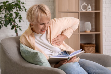 Mature woman having heart attack while sitting in armchair at  home