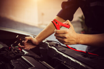 Electrical technician car mechanic holding booster cables for jump start car for empty battery dead and low power problem or fix and service maintenance accident assistance engine doesn't start.