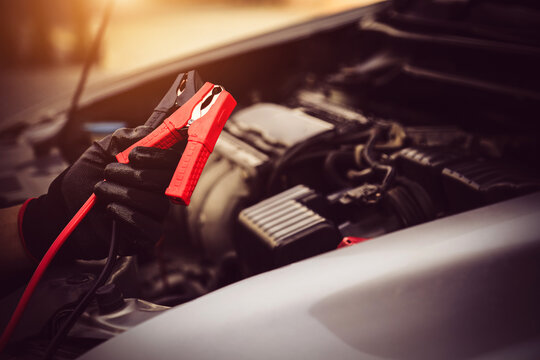 Electrical technician car mechanic holding booster cables for jump start car for empty battery dead and low power problem or fix and service maintenance accident assistance engine doesn't start.