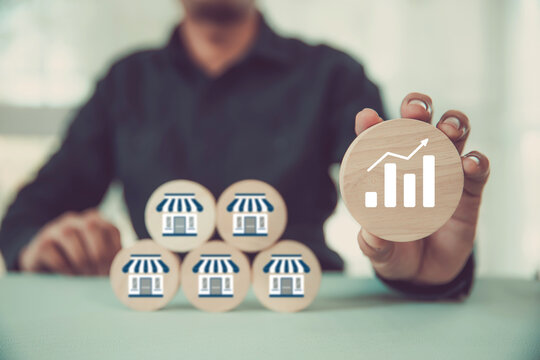 Hand choose wooden toy stack with franchise icon and graph for goal to growth investment planning financial and branch expansion and management plan bank loans or marketing franchising business.