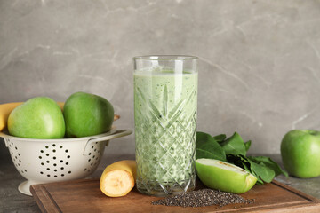 Glass of fresh spinach smoothie with apples, banana and chia seeds on grey background
