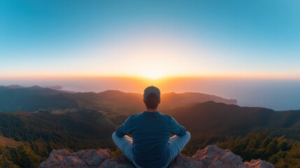 Obraz premium A man is sitting on a mountain top, looking out at the ocean