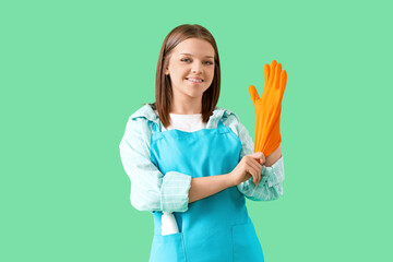 Female janitor putting rubber glove on green background