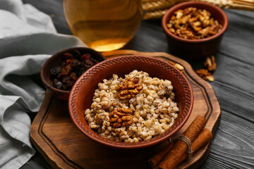 Bowl of traditional Ukrainian Kutya dish with walnut and cinnamon on black wooden background