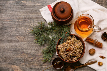Bowl of traditional Ukrainian Kutya dish with Christmas tree branches and jug of uzvar on wooden background