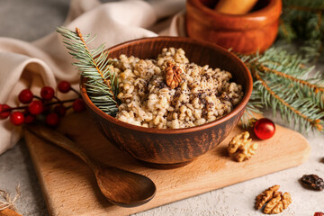Bowl of traditional Ukrainian Kutya dish with fir branches and Christmas balls on white background