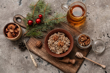 Bowl of traditional Ukrainian Kutya dish with fir branch and jug of uzvar on grey background