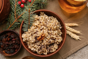 Bowl of traditional Ukrainian Kutya dish and Christmas tree branches on grey background