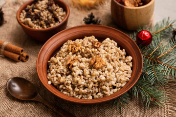 Bowls of traditional Ukrainian Kutya dish with cinnamon and Christmas tree branch on grey background