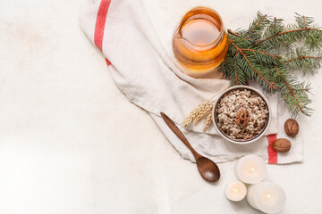 Bowl of traditional Ukrainian Kutya dish with burning candles and jug of uzvar on white background
