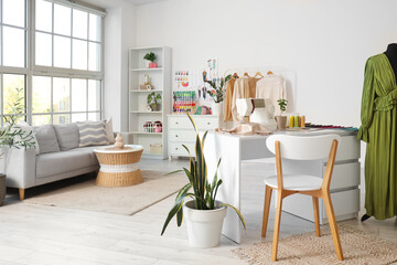 Interior of atelier with tailor's workplace, clothes and sofa