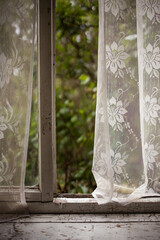 View from the window through white curtains on a spring summer landscape on a balcony