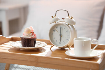 Tray with breakfast and alarm clock in bedroom, closeup