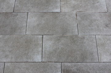 Texture of square paving tile. Pattern of tiles in the street. Close up of gray concrete pavers background.