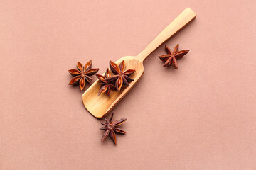 Wooden scoop with aromatic star anise on color background