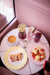 Healthy breakfast served with coffee cappuccino and milkshake, cottage cheese pancakes and piece of cake in a cafe with kinfolk style interior. Breakfast concept.