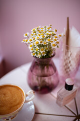 Lots of little daisies in a pink glass vase on served table of the cafe
