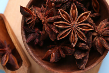 Wooden bowl and scoop with aromatic star anise, closeup