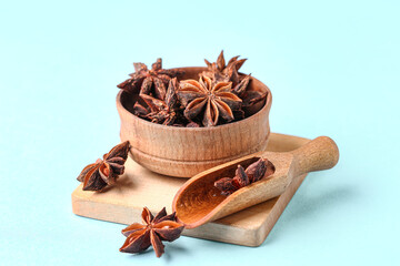Wooden bowl and scoop with aromatic star anise on color background