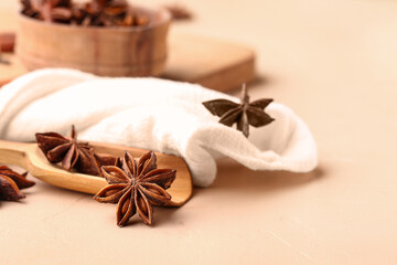 Wooden scoop with aromatic star anise spice and napkin on color table