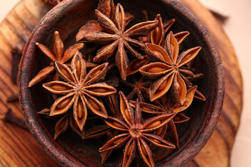 Wooden board with bowl of aromatic star anise, closeup