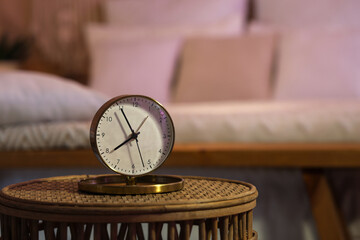 Golden alarm clock on table in bedroom at night, closeup