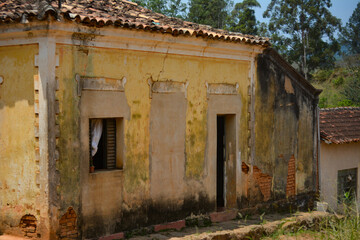 An old colonial house, weathered and decayed over time, with cracked walls and faded paint. The rustic textures and muted colors emphasize its historical charm and abandonment.