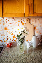 White chrysanthemums in a glass vase in the kitchen. Still life