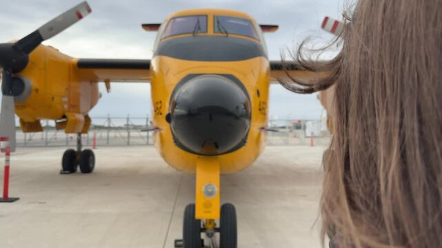 A girl looks at a Canadian aircraft De Havilland Canada CC-115 Buffalo