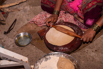 A village woman makes bread on the stove. cooking bread in clay stove , chula , makeing bread , roti , in village