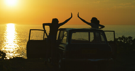 People, car and high five with beach sunset for holiday, vacation or stop at destination in nature. Friends, tourist or silhouette with freedom for sightseeing journey or adventure by ocean coast