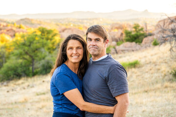 Couple embraces in a serene outdoor setting during golden hour near rocky landscape