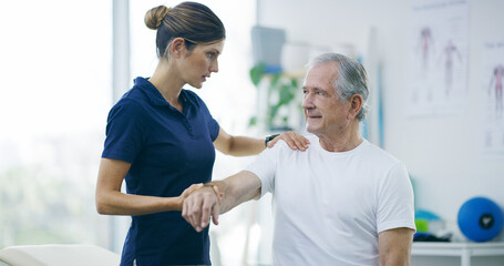 Physiotherapy, woman and senior man with shoulder pain for stretching, help and care in office. Chiropractor, elderly patient or advice in practice for rehabilitation, healing or arm exercise in exam