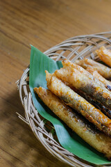 photo of serving aromatic banana snack or layered banana on a wicker plate lined with fresh green banana leaves on varnished wood. photo taken from a high angle