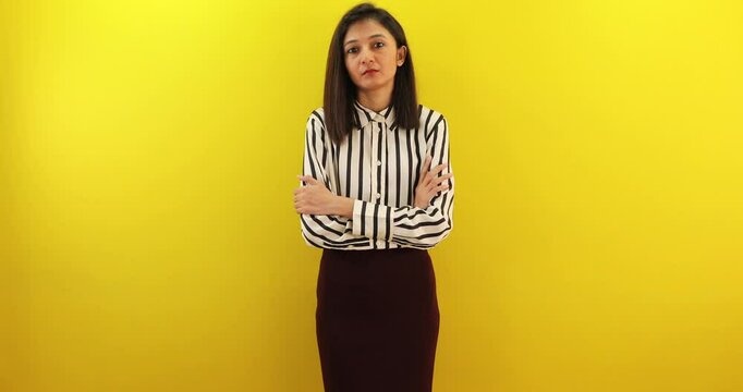 Pensive young woman crossed arms with angry face expression, looking at camera on yellow background.