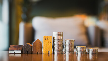 A model of a wooden house and coins placed in a stack, staggered in order to make it prone to falling. The concept of risk in real estate investment that is related to the value of money.